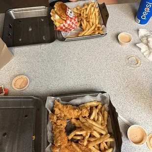 two trays of fried chicken and fries
