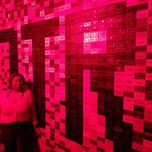 a woman standing in front of a wall covered in red lights