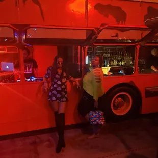 two women standing in front of a double decker bus