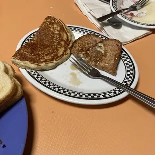 Half eaten pancake and blueberry French toast.