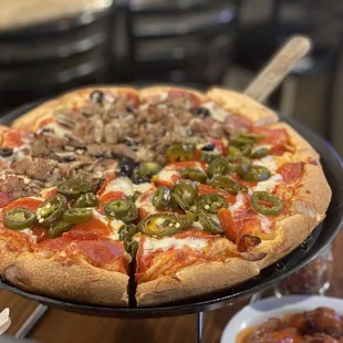 a pizza with pepperoni, mushrooms, jalapenos, and other toppings