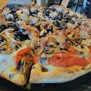 a pizza with mushrooms and black olives