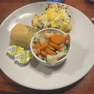Loaded chicken breast with steamed vegetables and a roll