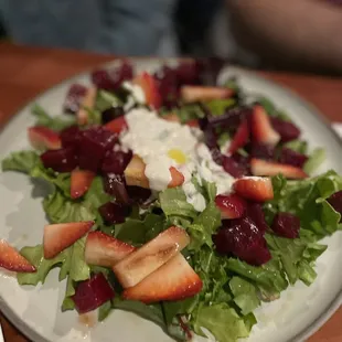a plate of salad with strawberries and goat cheese