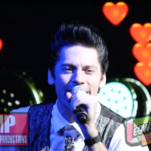 a man in a vest singing into a microphone