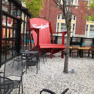 a red chair in the middle of a gravel patio