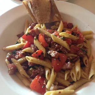 a plate of pasta with tomatoes and bread