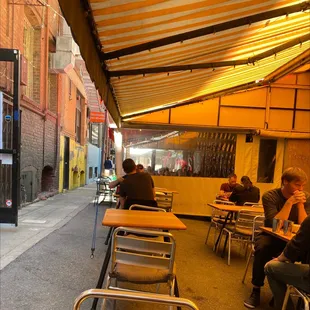 people sitting at tables outside a restaurant