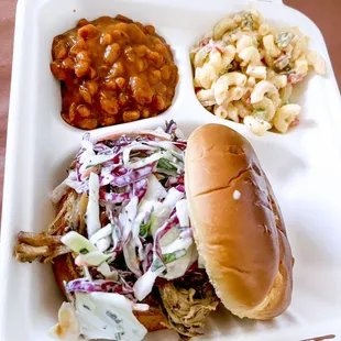 a pulled pork sandwich with coleslaw and macaroni salad