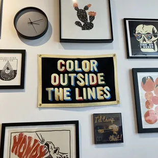 Gallery wall of art, "Color outside the lines" featured prominently.