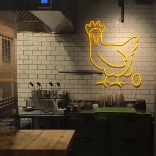a kitchen with a neon chicken sign
