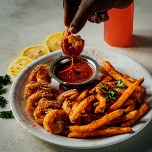 a person dipping sauce onto a plate of fries