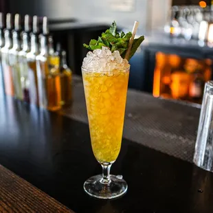 a tall glass filled with a drink and garnished with mint