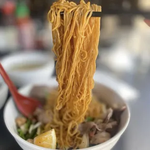 a bowl of noodles with chopsticks