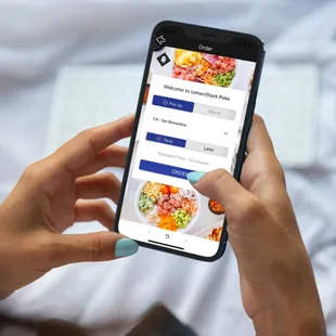 a woman&apos;s hand holding a phone with food on it
