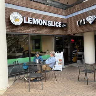two people sitting at a table outside