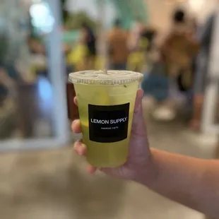 a hand holding a cup of lemon juice