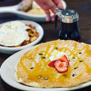 a plate of pancakes with strawberries and eggs