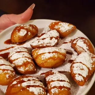a plate of powdered sugared donuts