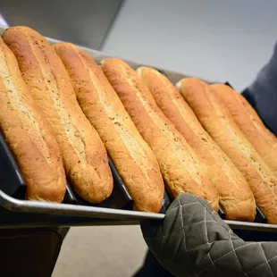 a person holding a tray of breadsticks