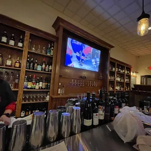 a woman behind a bar with bottles of wine