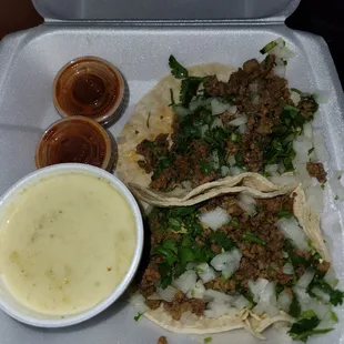 2 soft ground beef tacos with a side of queso.