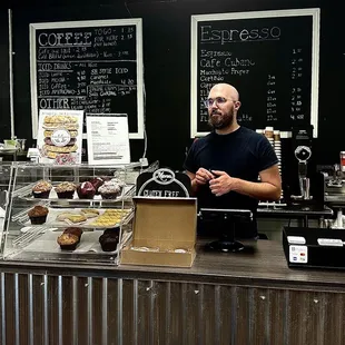 Zach Leonard, owner,  taking an order.  Menu board with pricing hangs behind him.