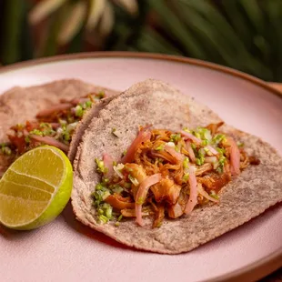 two tacos on a pink plate