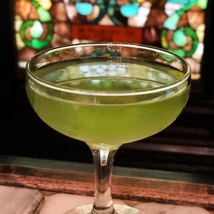 a green cocktail in a coupe glass