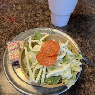 a plate of salad with pepperoni