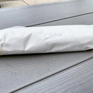 a sandwich wrapped in paper on a picnic table
