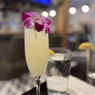 a glass of champagne with a flower garnish