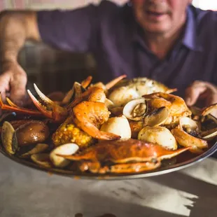 a man holding a plate of crabs