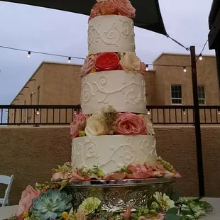 Wedding cake in buttercream with piped frosting details, and fresh flowers.