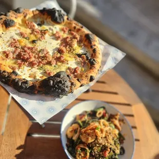 a plate of food and a pizza on a table