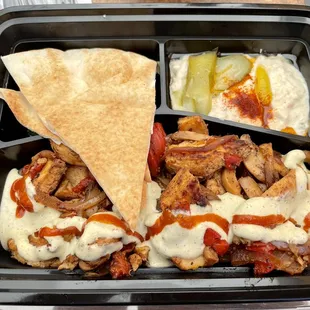 Clockwise: pita 2 pieces with salad underneath, hummus with pickle and pepper, chicken shawarma atop saffron rice