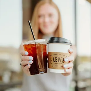 a woman holding two cups of coffee