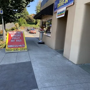 a sidewalk with a sign for a business