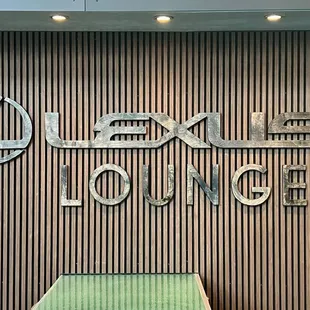 a green bench in front of a sign that reads lexus lounge