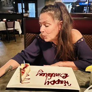 a woman sitting in front of a birthday cake