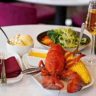 a lobster, corn and a glass of wine
