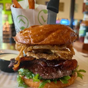 a hamburger with bacon, lettuce, and onion rings