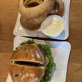 Burger with onion rings and side of ranch dressing for dipping rings in