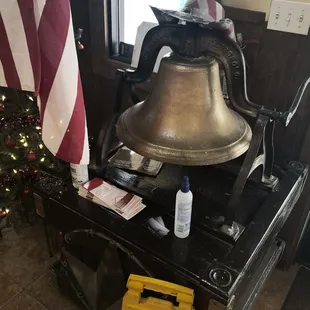 a large bell with a caution sign next to it