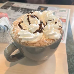a cup of hot chocolate with whipped cream and chocolate drizzle