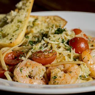 a plate of pasta with shrimp and tomatoes