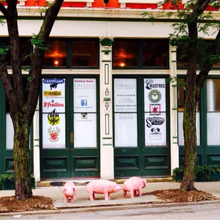 three pink pigs on the sidewalk