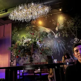 a man sitting at a bar with a chandelier in the background