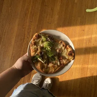 a person holding a plate of pizza