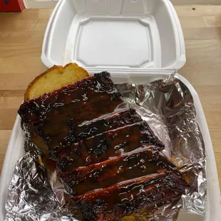 a piece of barbecued meat in a styrofoam container